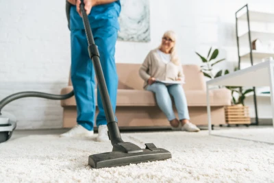 Man Vacuuming while woman sits and watches
