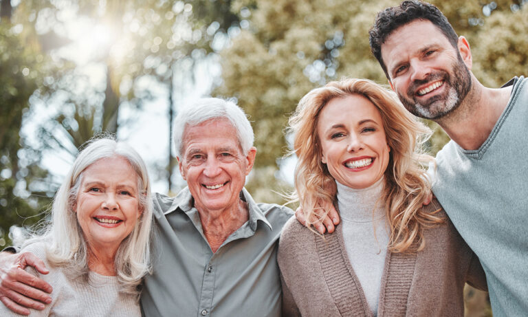 Adult siblings standing with their smiling older parents outdoors, representing family support and caregiving decisions.