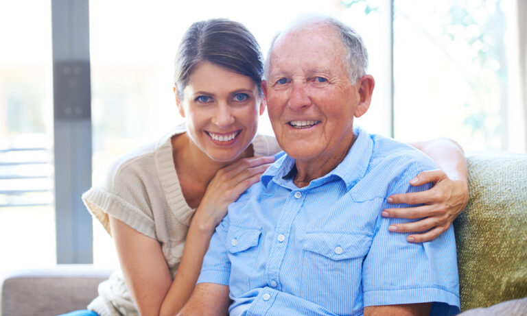 Daughter sitting with and hugging her elderly father at home, showing support and companionship in a home care setting