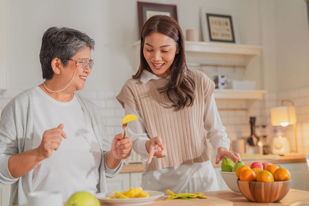 Senior woman and a companion preparing fresh fruit together in a home kitchen