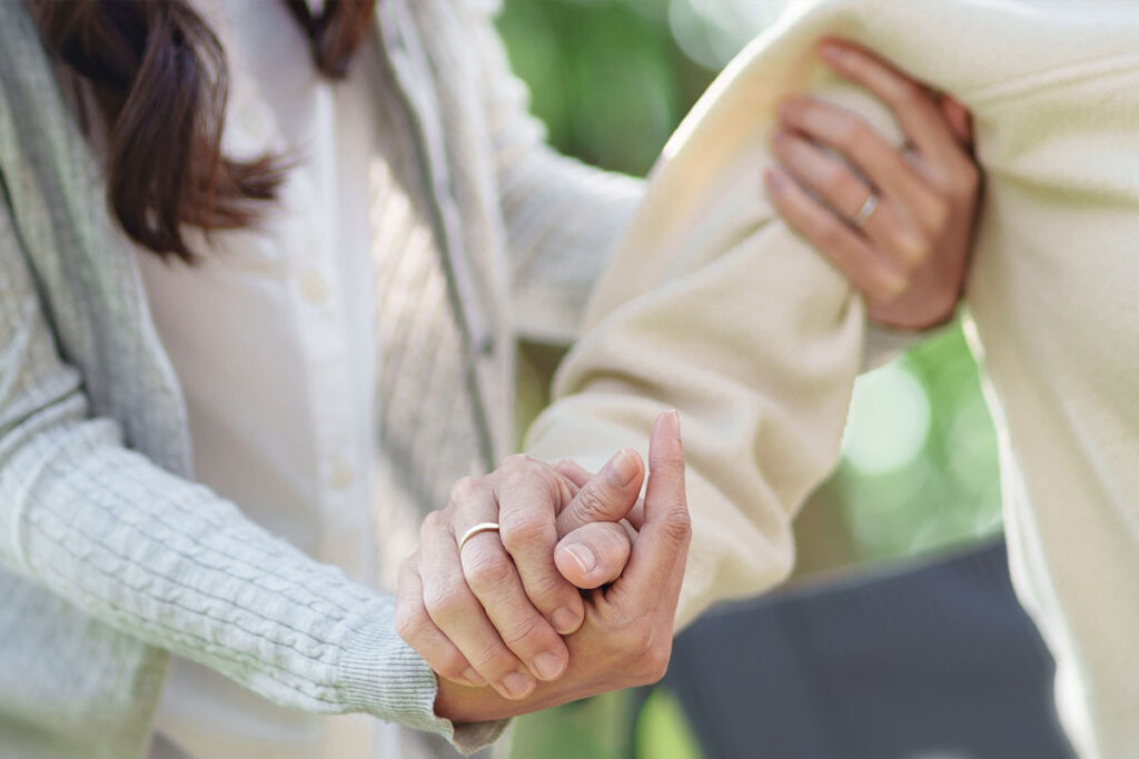 Caregiver holding the hand of a senior woman while supporting her arm at home