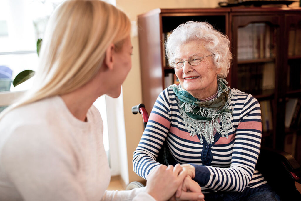 Caregiver talking warmly with a smiling senior woman at home