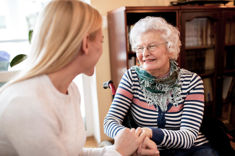 Caregiver talking warmly with a smiling senior woman at home